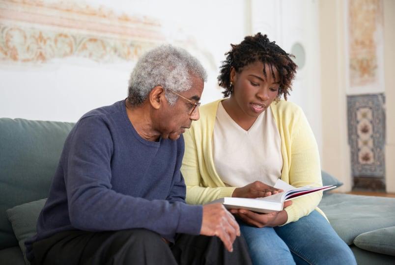 A grandfather and granddaughter looking at a book